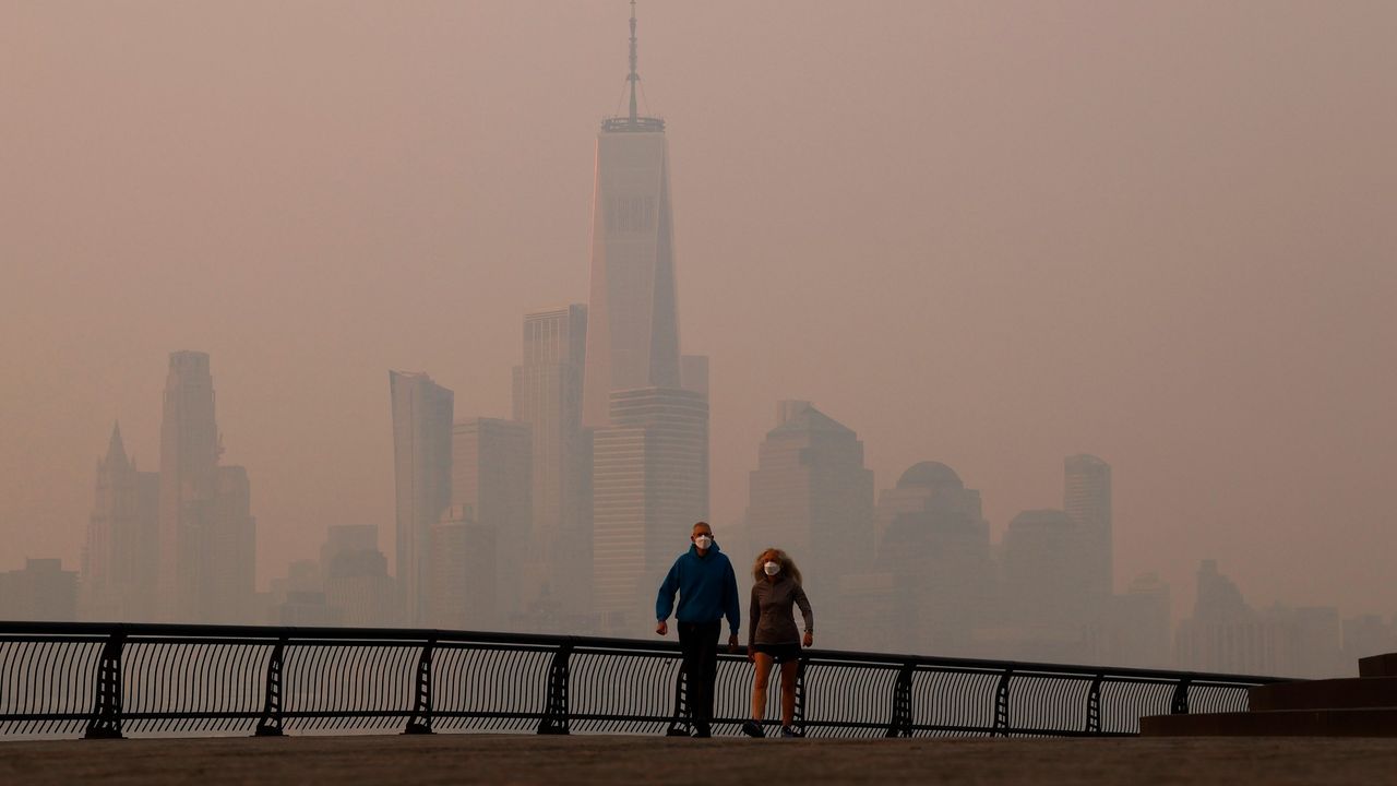 Smoke along the Hudson River with two people walking.