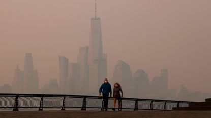 Smoke along the Hudson River with two people walking