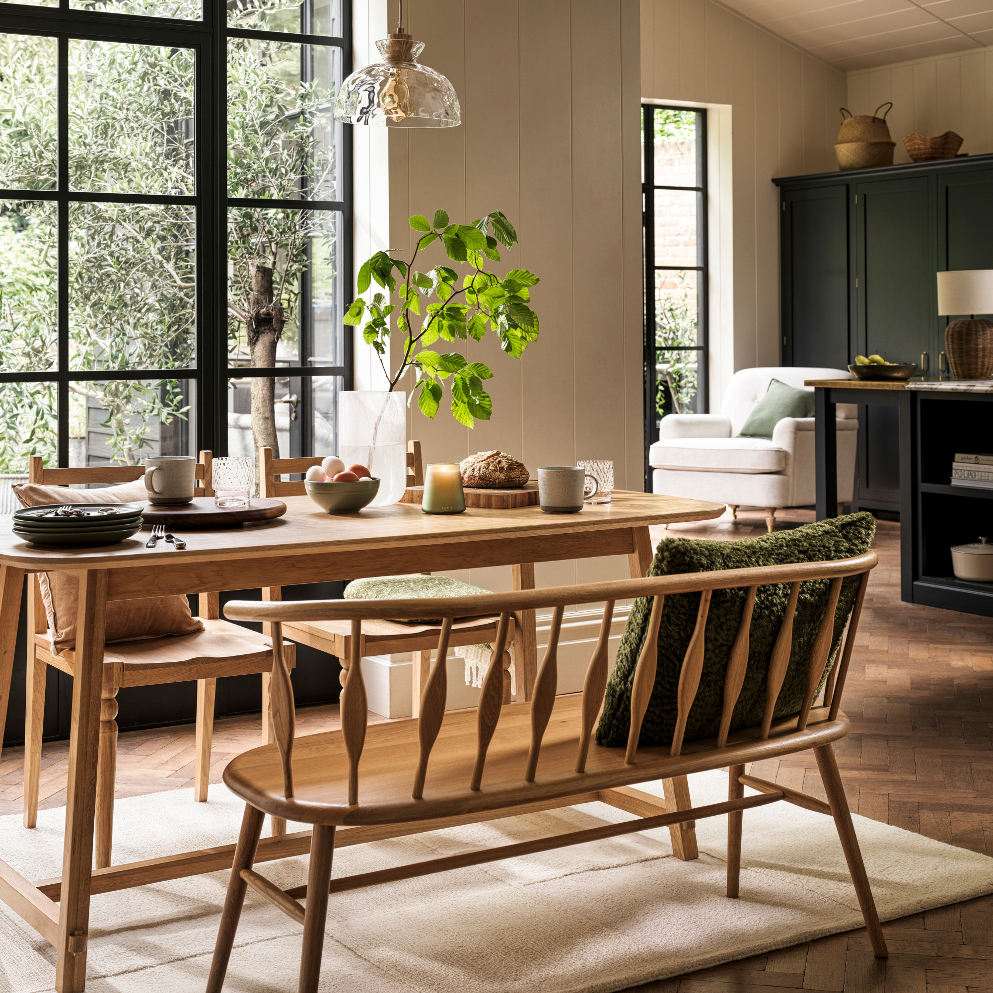 an open plan kitchen diner with wooden dining table and chairs in front of crital doors