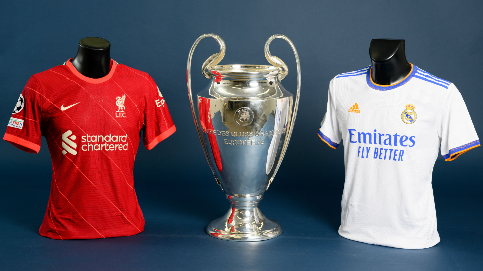 Liverpool vs Real Madrid shirts either side of the Champions League trophy