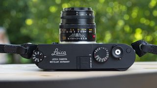 Leica M11-P top view on wooden table with 50mm f/2 lens attached