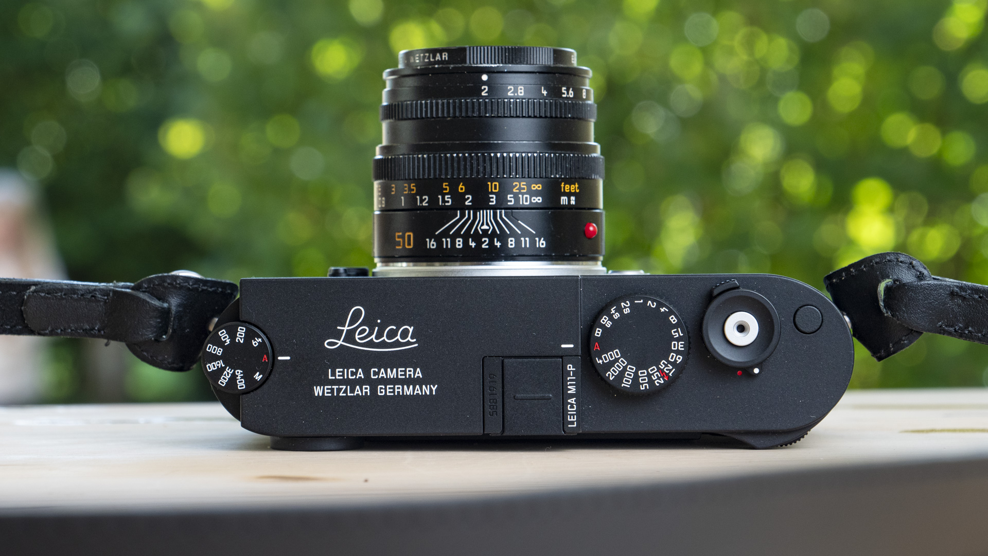 Top view of Leica M11-P on a wooden table with a 50mm f/2 lens mounted