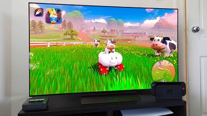 Switch 2 connected to LG OLED C5 on black TV unit with Mario Kart World gameplay on screen featuring character Cow in centre. 