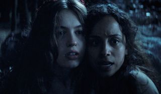 Olivia Welch and Kiana Madeira huddled together in the woods in Fear Street: Part 3 - 1666.