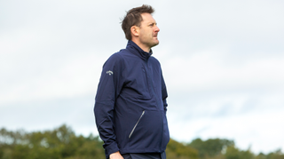 A golfer poses in the Callaway Premium Full Zip Wind Jacket