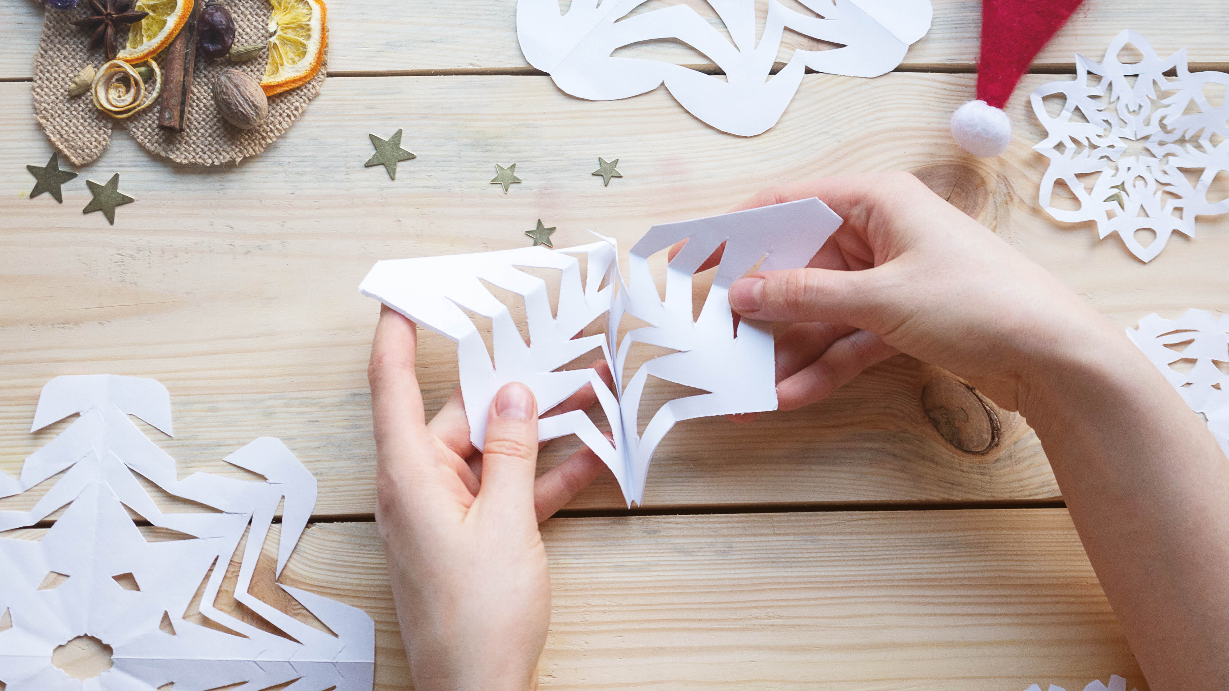 Woman holding a white paper snowflake that has been handmade