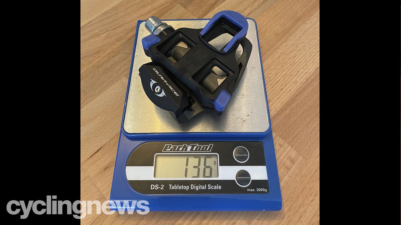 a Shimano Dura-Ace pedal and blue cleat on a Park Tools scale showing a weight of 136 grams