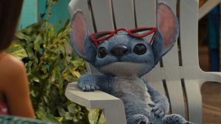 Lilo sitting on a white chair with red sunglasses perched on his head in Disney's Lilo & Stitch live-action remake