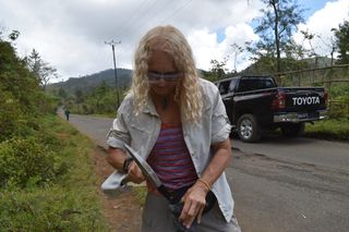 Cornelia Class of the Lamont-Doherty Earth Observatory uses a rock hammer to break apart a sample on the side of a road in Anjouan.