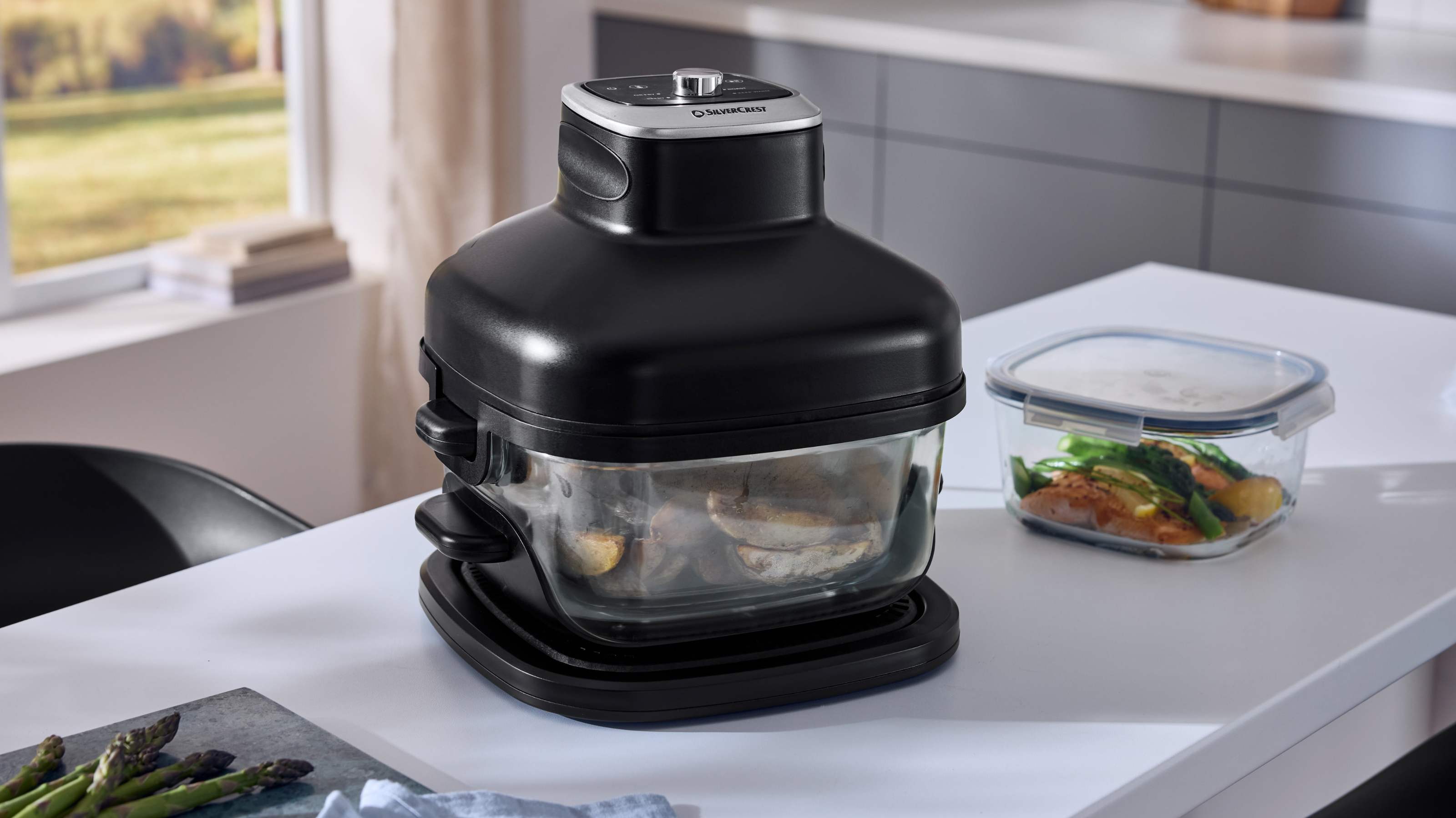 Lidl glass air fryer cooking wedges. Next to it is a glass container of cooked salmon and greens.