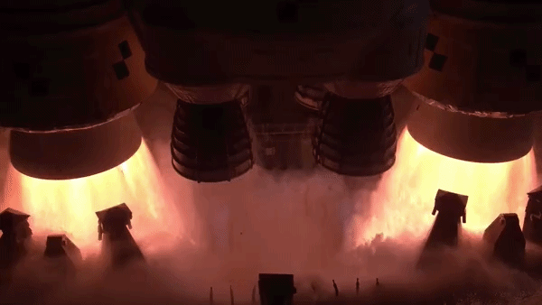 two massive side booster spew yellow orange fire lifting the core stage of a rocket as the main engines also ignite 