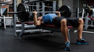 Man performing a barbell bench press with the bar close to his chest