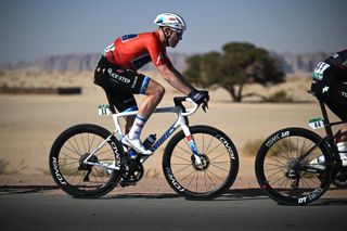 Cyclist riding side on in red jersey with white bike