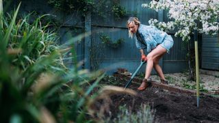 Gardener digging over soil in a small backyard