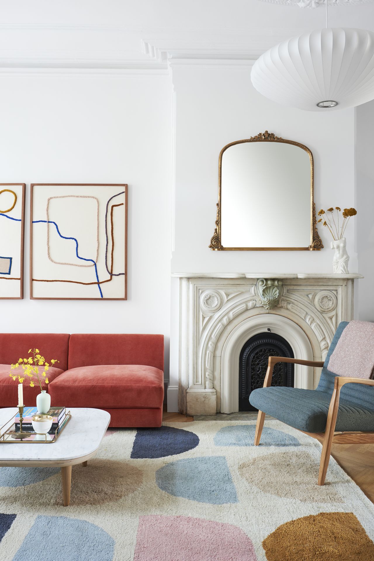 a white living room with abstract artwork and a bright red sofa