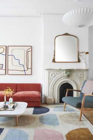 a white living room with abstract artwork and a bright red sofa