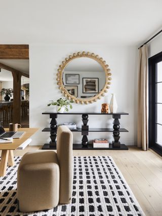 dining room with round mirror, black console, dotted rug