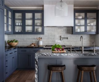 blue kitchen with glazed cabinets and marble island