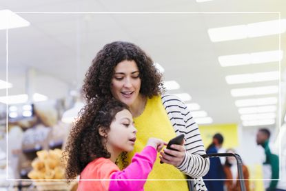 mother and daughter looking at smartphone in a supermarket