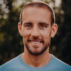 A headshot of Scott Schrader - a man wearing a blue jumper smiling into the camera