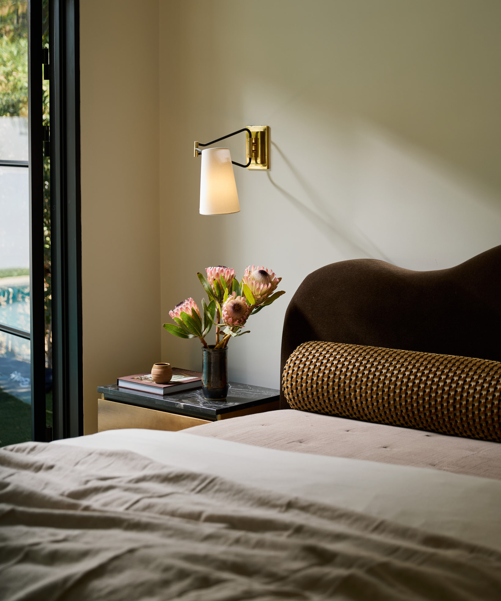 bedroom with scalloped headboard and gold wall light