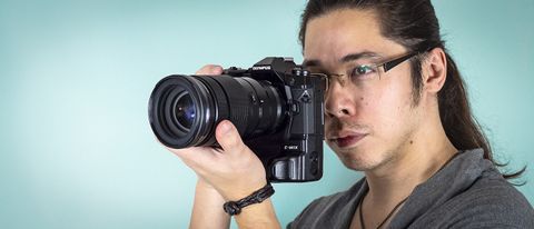 Reviewer James Artaius holding the Olympus M.Zuiko 40-150mm f/2.8 Pro lens, mounted to the Olympus OM-D E-M1X