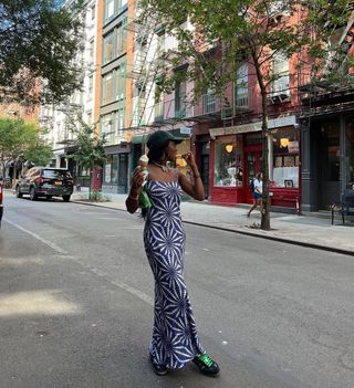 woman wearing printed slip dress, baseball hat, and sneakers outfit