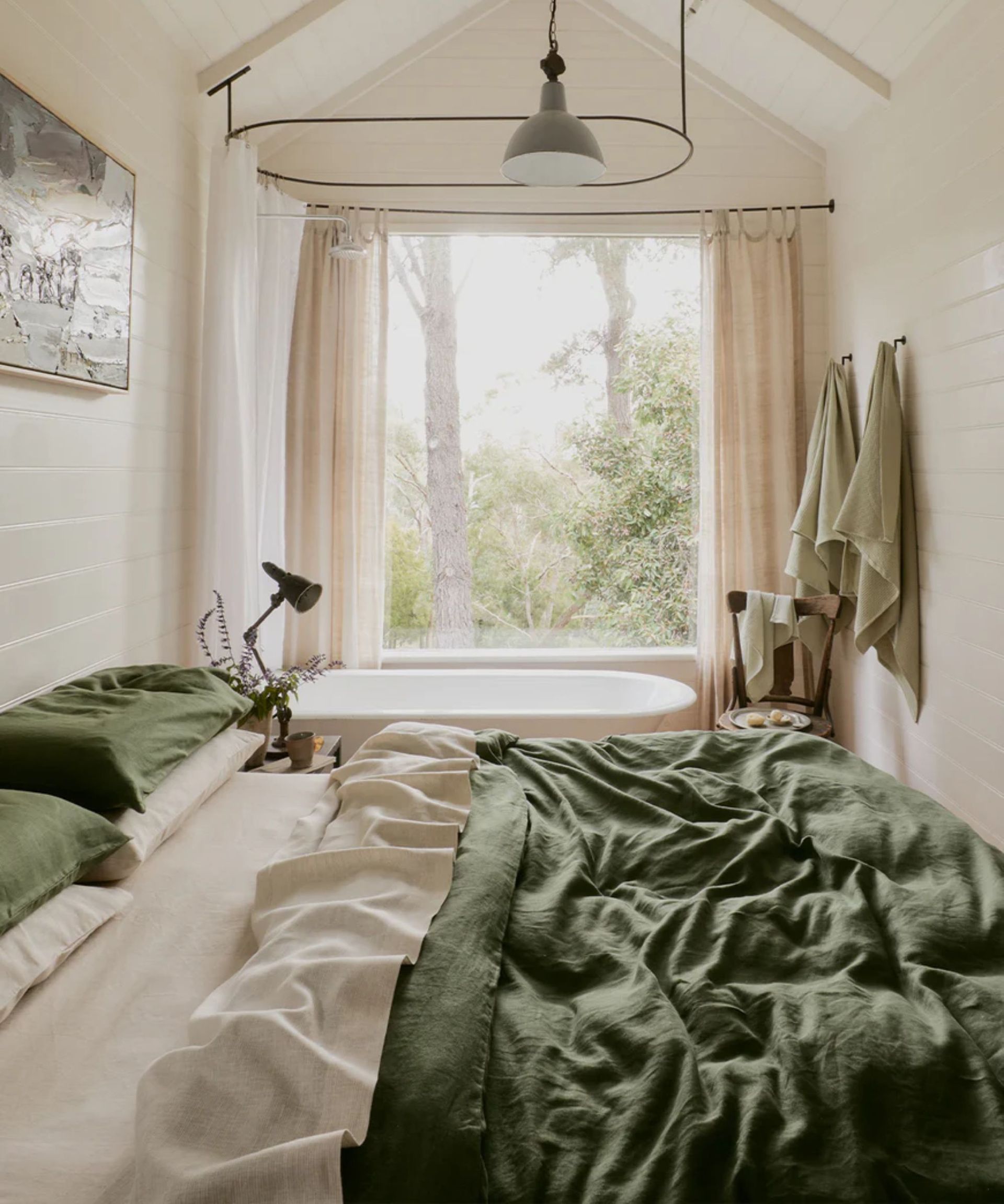shiplapped small bedroom with forest green linen bed sheets and a free standing bathtub