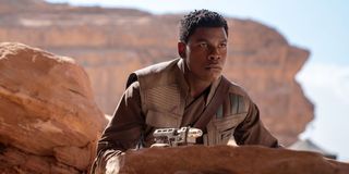 Finn (John Boyega) crouches behind a rock in 'Star Wars: The Rise of Skywalker'