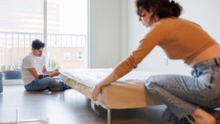 A couple putting a new mattress cover on a mattress and repairing it