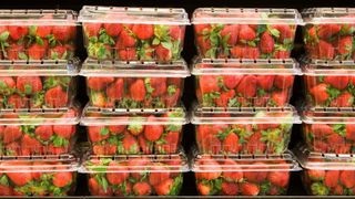 photo of plastic containers of strawberries in grocery store refrigerator