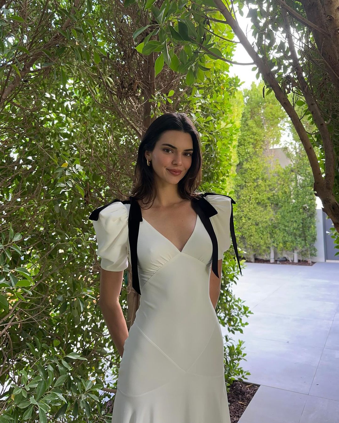Kendall Jenner wears a white dress with black bows.