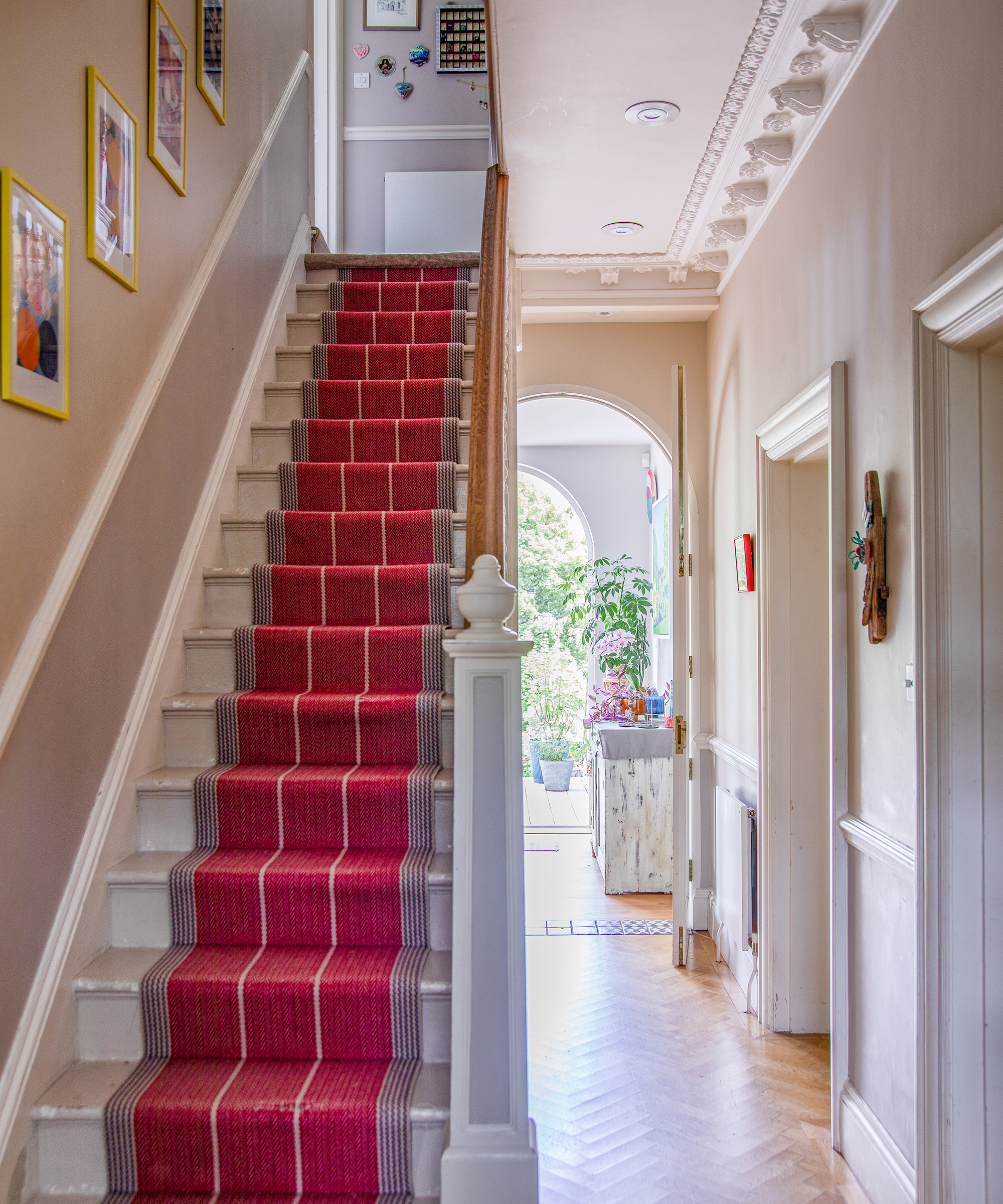 hallway in a period home with decorative plasterwork and striped stair runner
