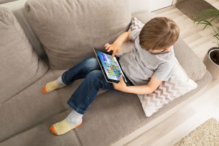 Kid sitting on a couch playing a tablet