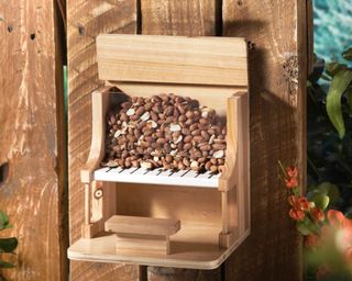 A wooden piano-shaped squirrel bird feeder