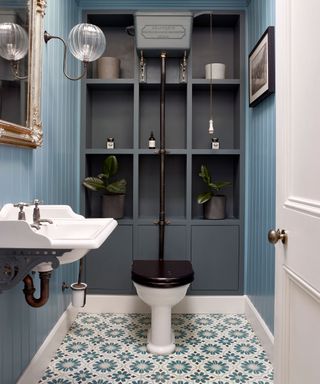 An example of cloakroom ideas showing a blue cloakroom with a patterned tiled floor, a gray storage wall and a white basin
