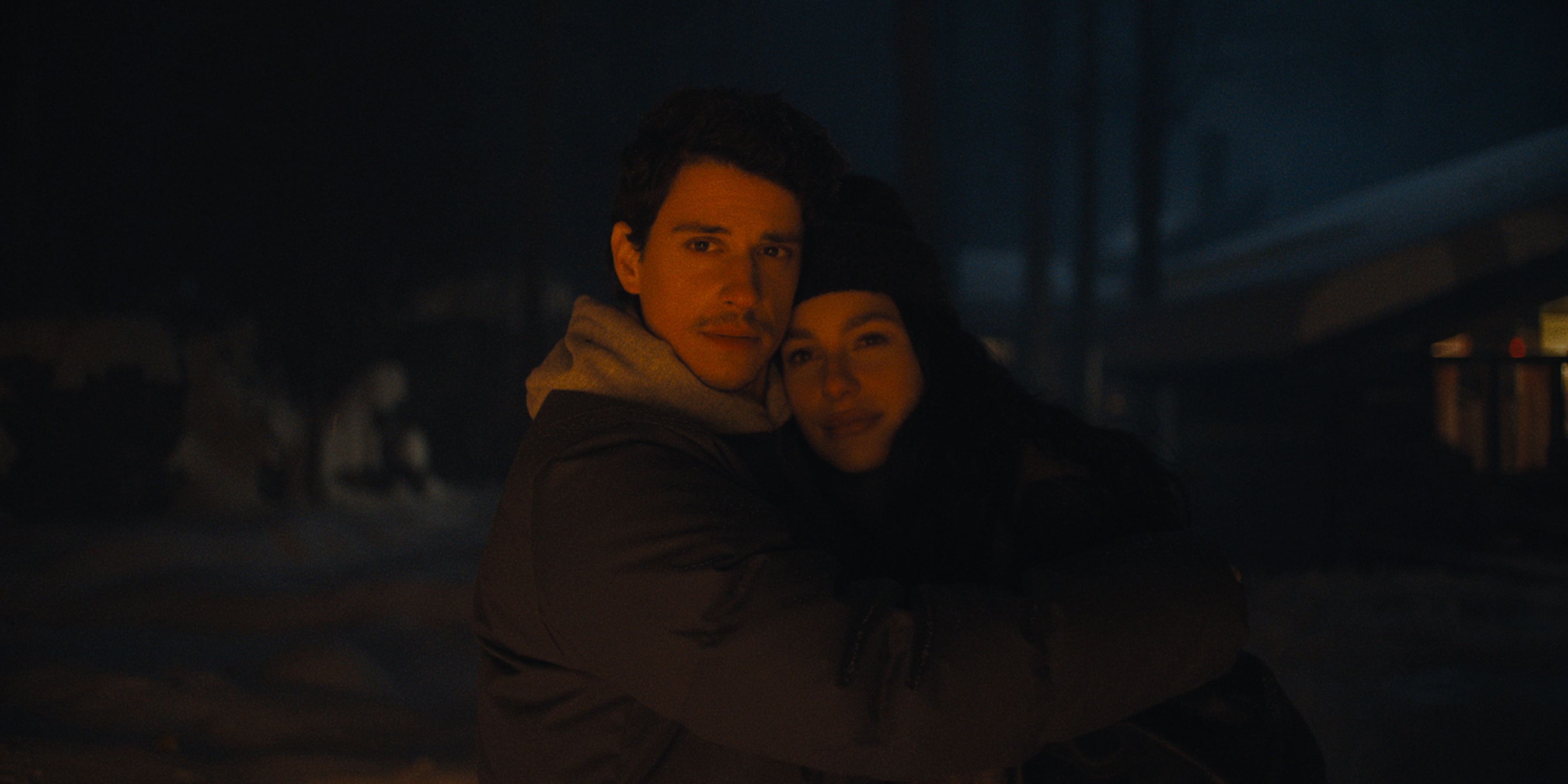 Adam DiMarco as Nicky Cunningham, Camila Morrone as Rachel Harkin in episode 103 of Something Very Bad Is Going To Happen as they hold each other in a wintery cold dark wood at night