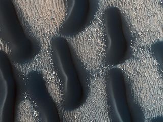 The dark rippled dunes of Mars' Proctor Crater likely formed more recently than the lighter rock forms they appear to cover.