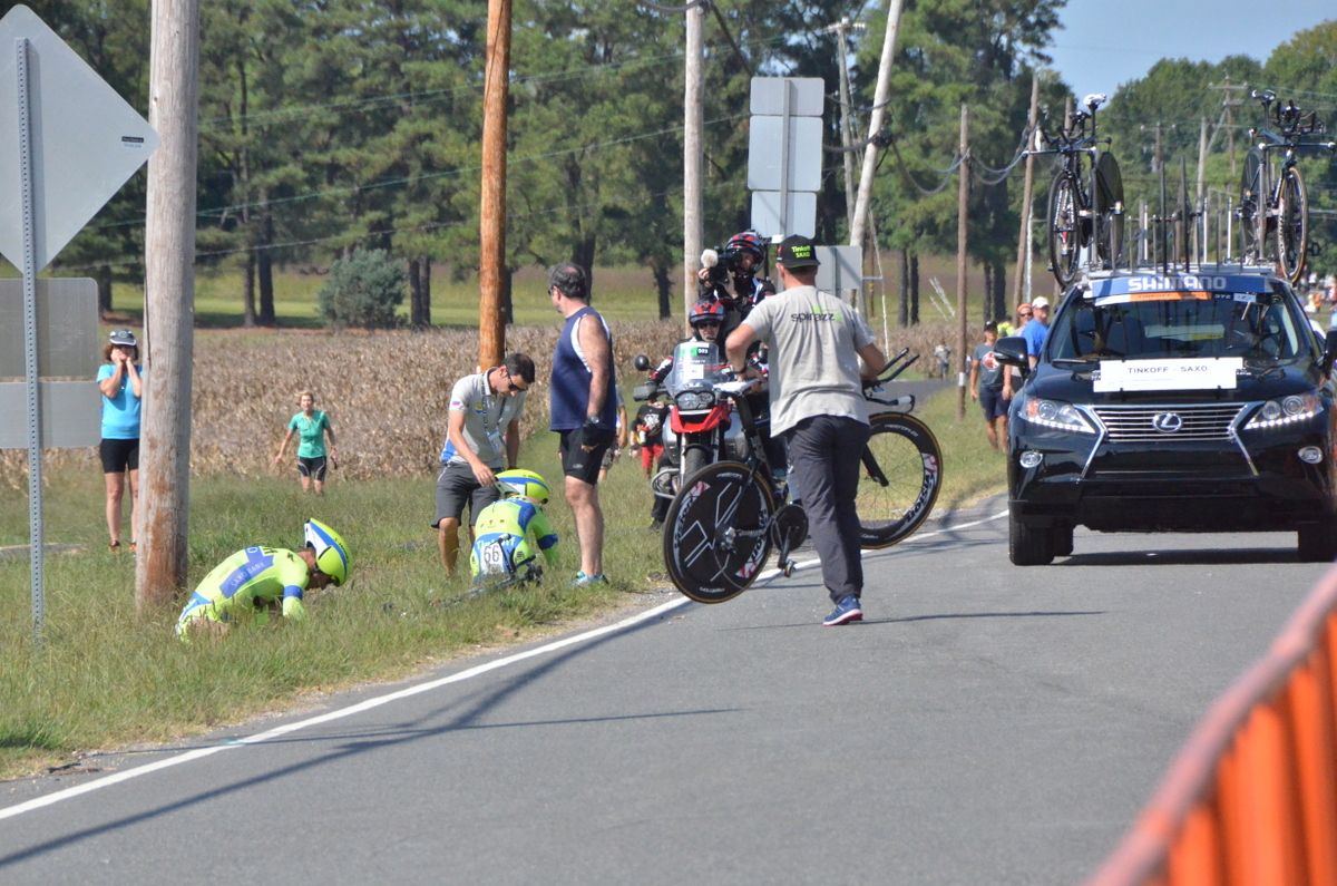 Michael Rogers and Michael Valgren in the grass after crashing as a Tinkoff-Saxo mechanic grabs a bike off the road