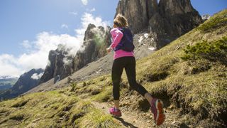 A woman trail running in a mountainous region