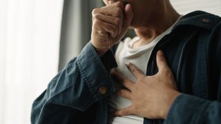 a man coughs and clutches his chest during an asthma attack