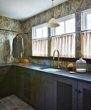 laundry room with built-in cupboards and rail and patterned wallpaper