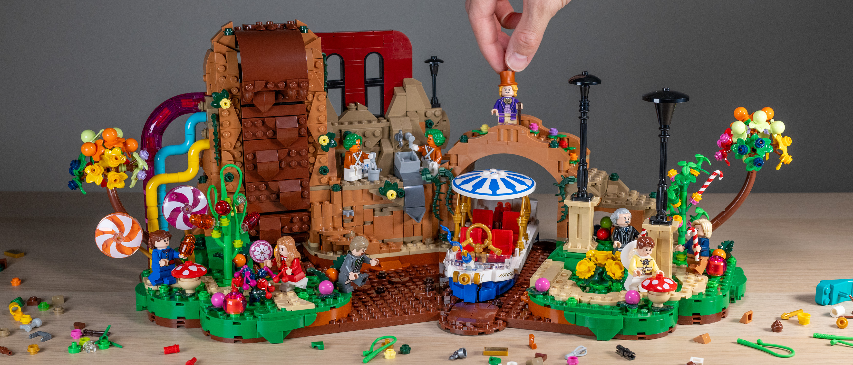 Lego Ideas Willy Wonka &amp; the Chocolate Factory (21360) set, front view with hand placing Wonka on bridge. 