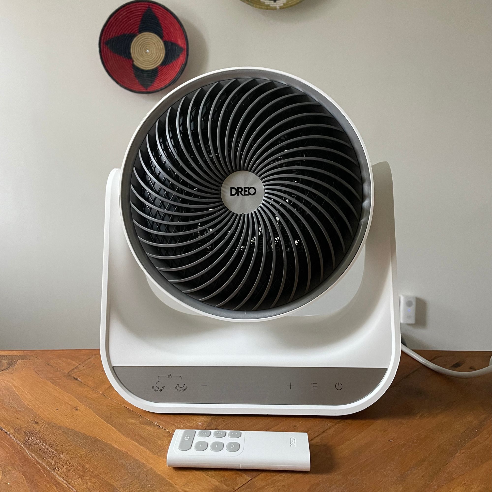 Dreo Smart Whole Room Heater 714S with the remote control sitting in front of it, on a wooden table