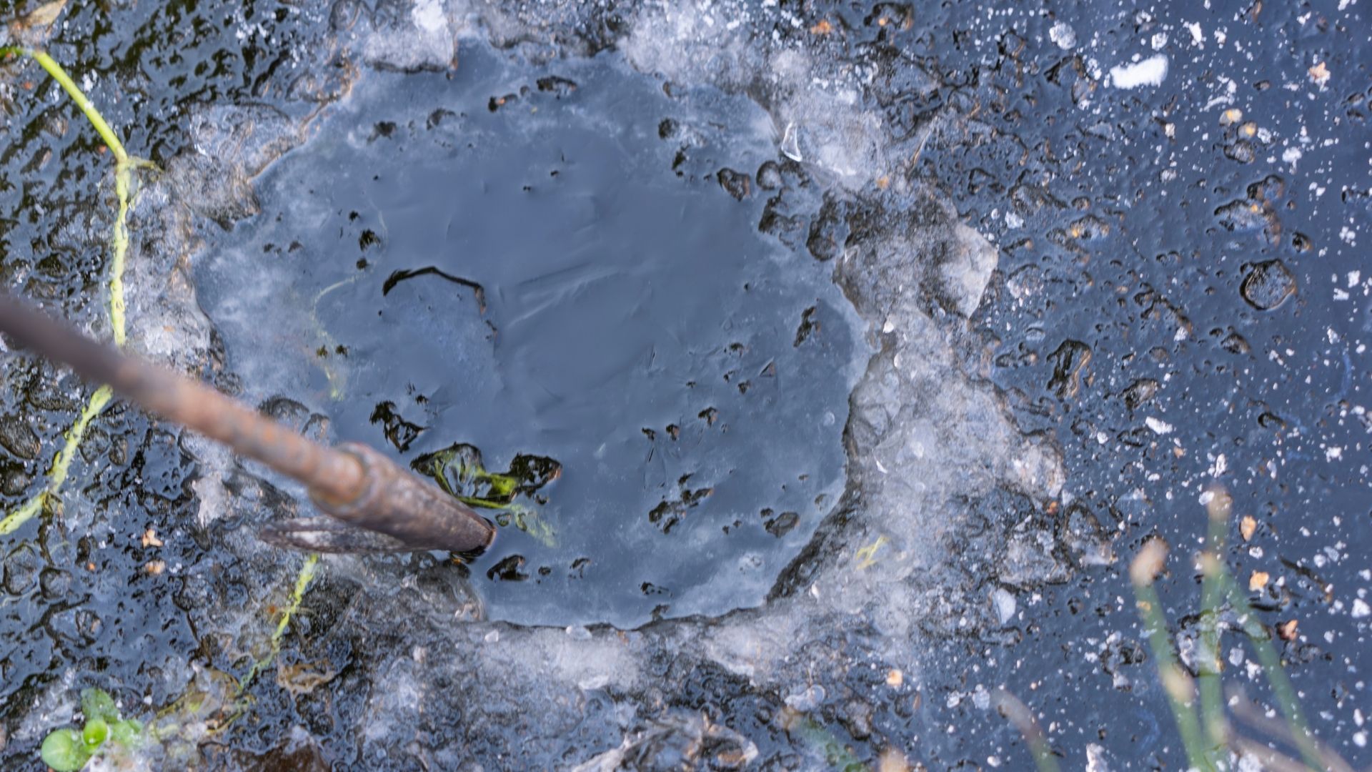 picture of someone making a hole in a frozen pond with iron poker