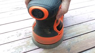 Close up on orange and black orbital sander on wooden table