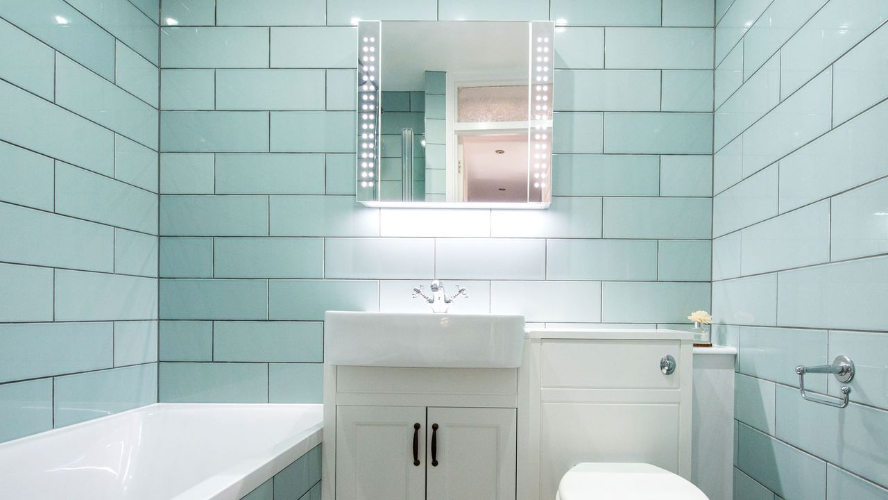 Mint metro tiles in bathroom with bath, vanity unit, toilet and mirror cupboard on wall