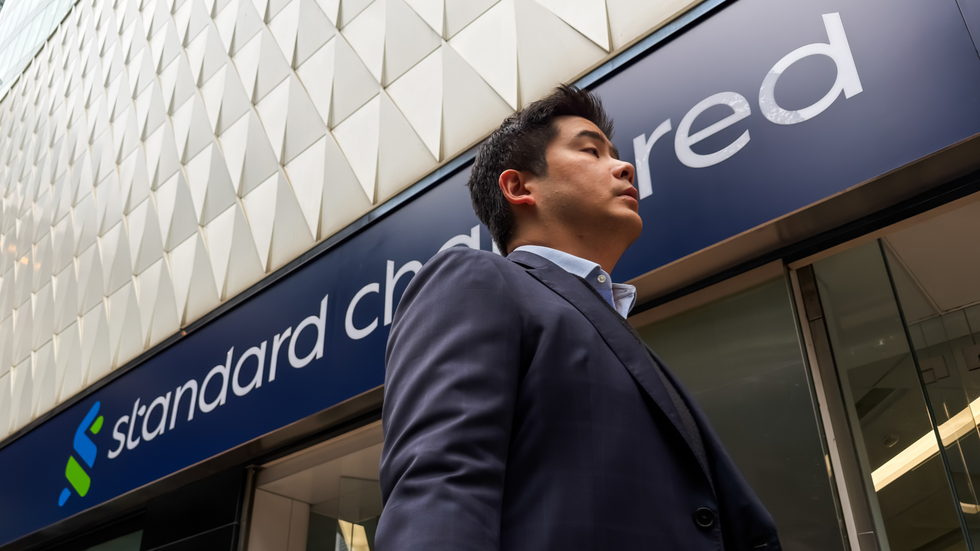 Standard Chartered bank branch with a person walking in front of it