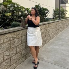 marina torres wears black tank top and white skirr and black flip flops 