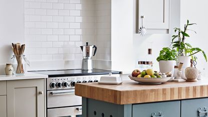 Butlers sink set into pale grey kitchen cupboards, pale grey splash back and copper taps